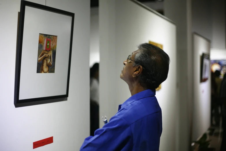 a woman looks up at the painting on display