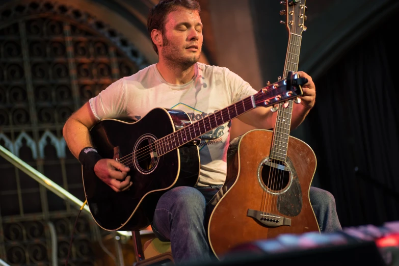 a man playing an acoustic guitar on a stage