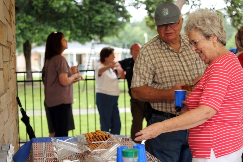 an old couple standing at a picnic table