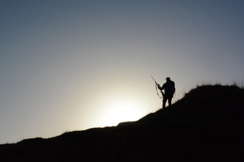 a silhouette of a man standing on top of a hill