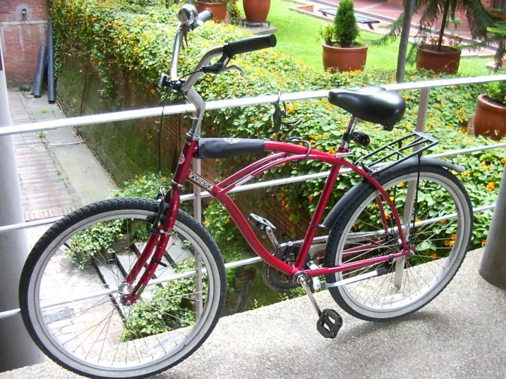 the bicycle is red and sitting next to the railing