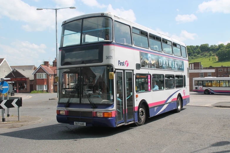 a double decker bus traveling past another bus