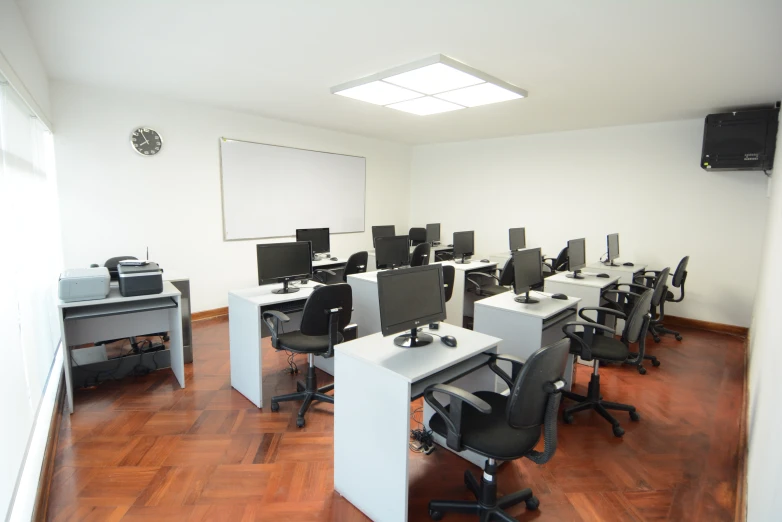 the large room has many computers, keyboards, chairs, and a projection screen