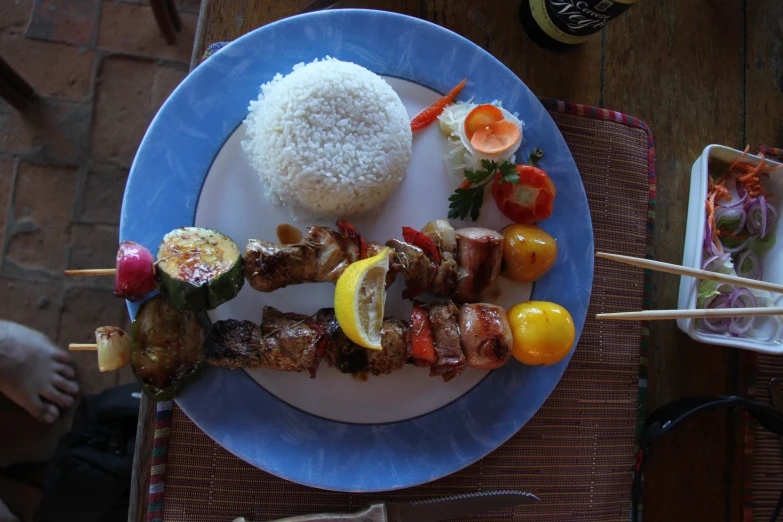 a dinner plate with meat and vegetable skewers
