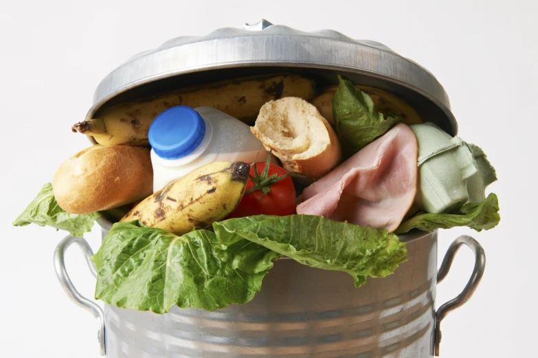 an aluminum trashcan is filled with some meat and vegetables