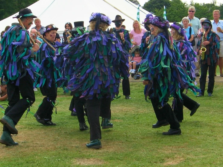 two groups of people in costumes standing on top of a green field