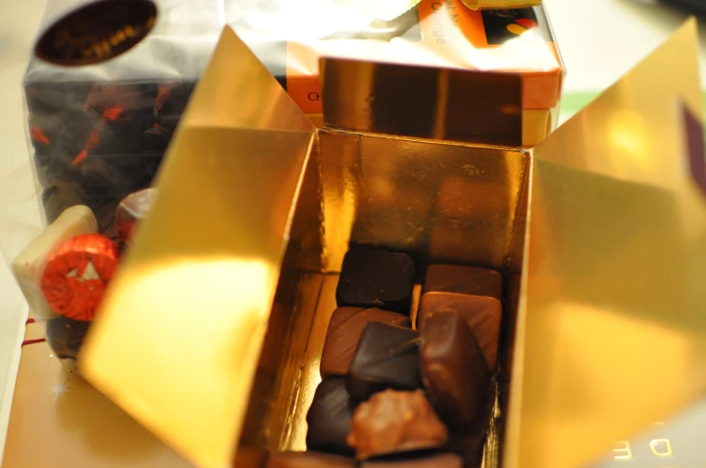 a golden box of chocolates with a gold handle