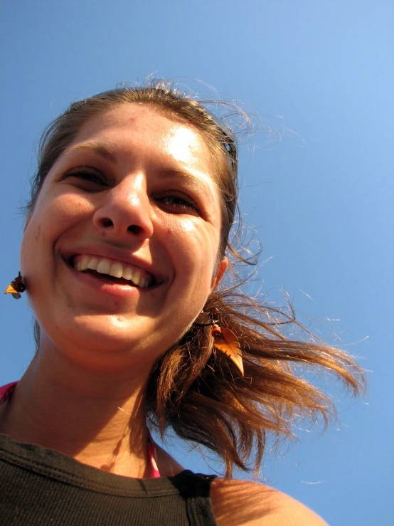 young woman smiling in the sunlight under blue skies