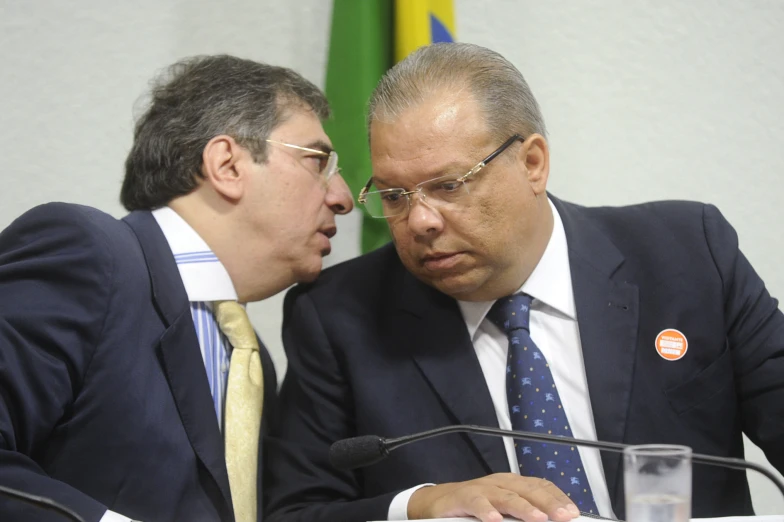 two men in suits and ties are sitting down at a table