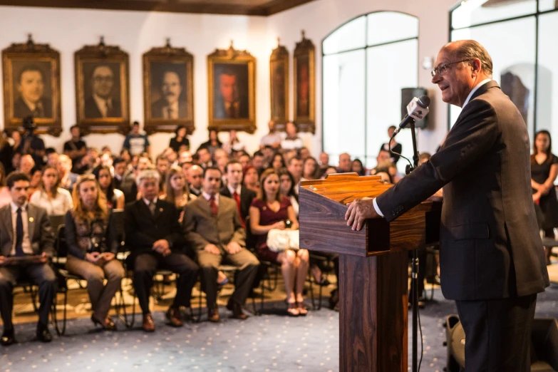 a man is standing at a podium in front of an audience