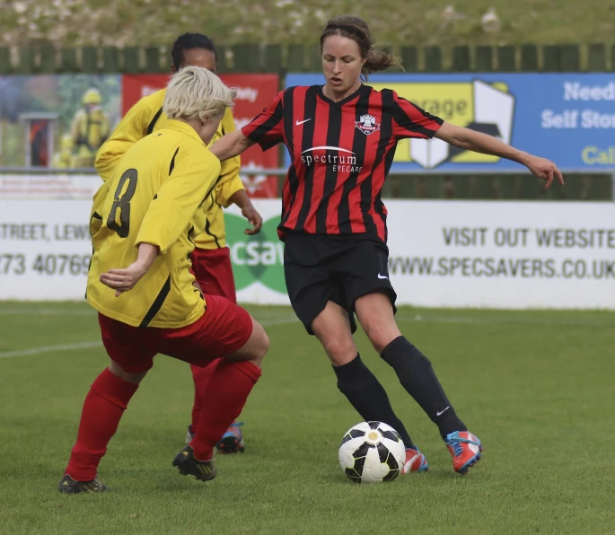 two female soccer players in a field near a ball