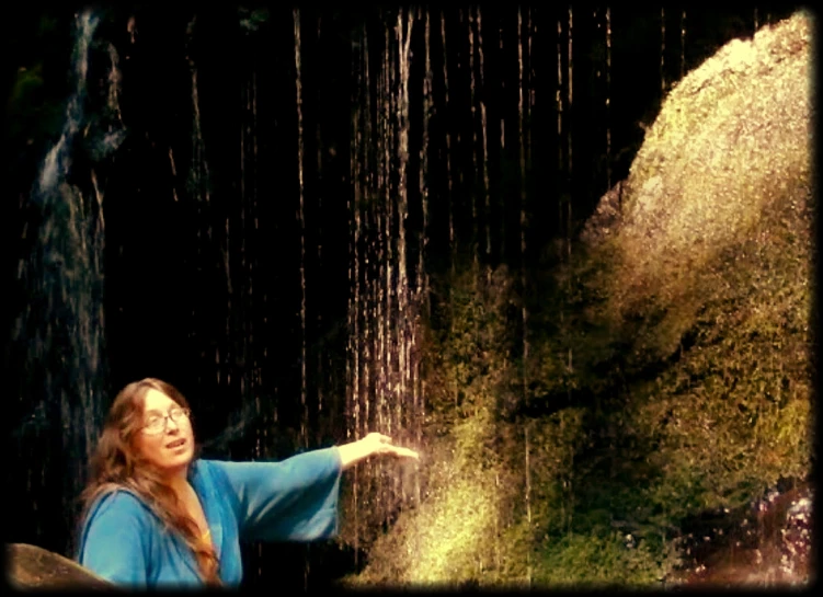 a woman is holding out her arm under the waterfall