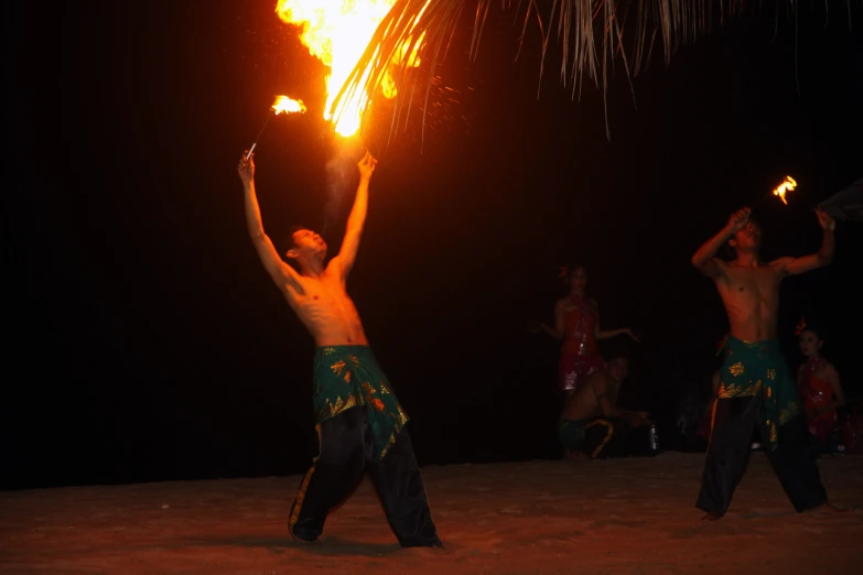 a couple of people standing on a beach holding fire