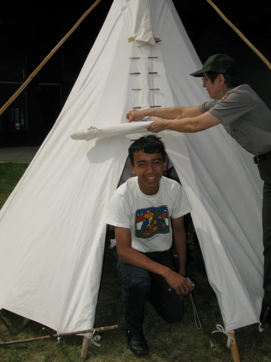 two people set up tents outside in the dark