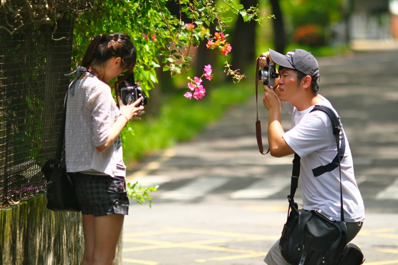 two people are outside with cameras and flowers