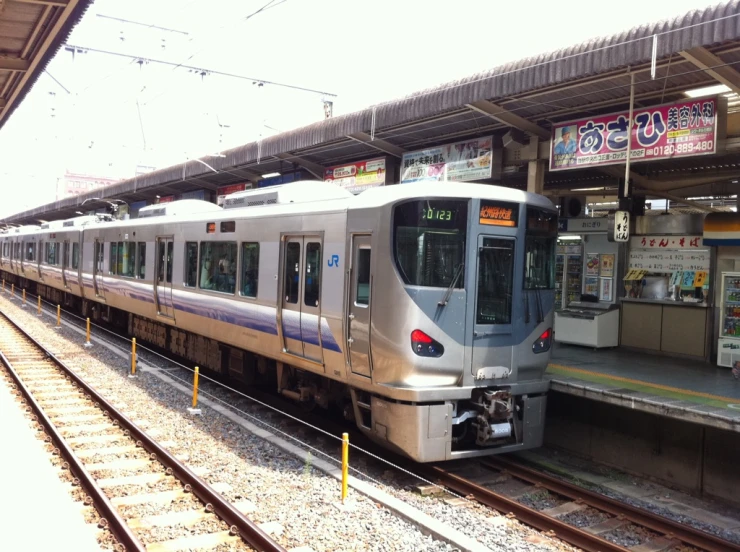 silver train stopped at train station, with signs in background