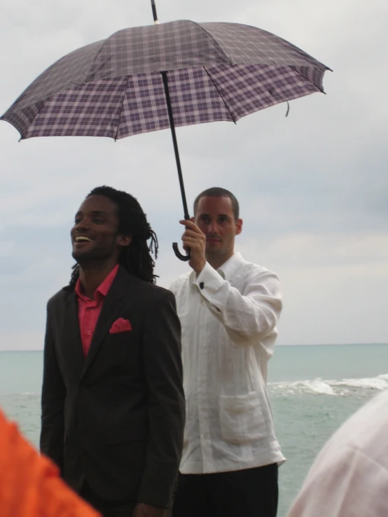 two men are standing together holding an umbrella