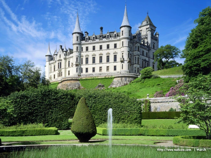 an old castle on the top of a hill surrounded by a garden