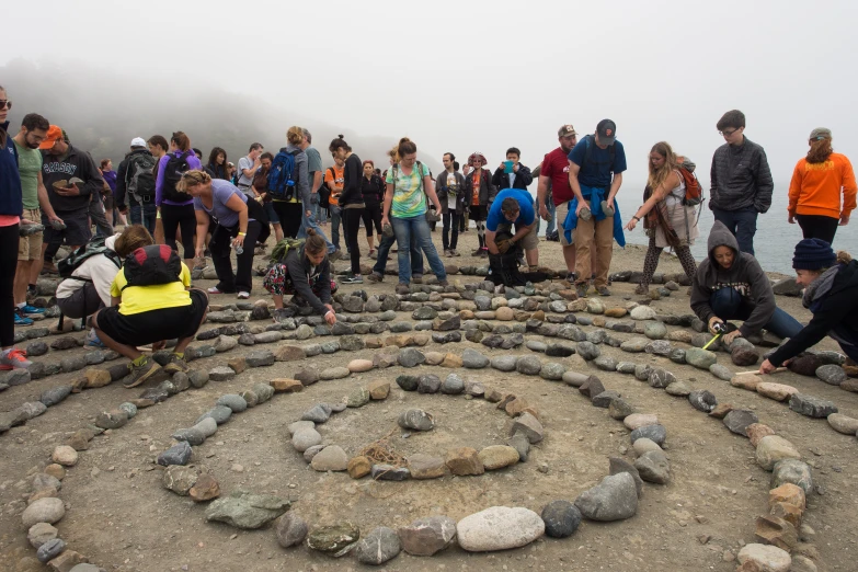 several people gathered together in front of a rock garden