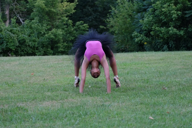 a woman is doing a handstand in the grass