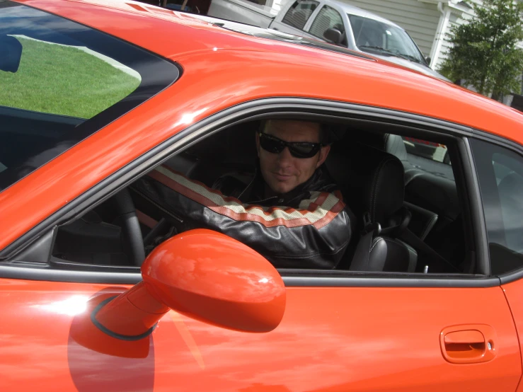 a man is sitting inside of a bright orange car