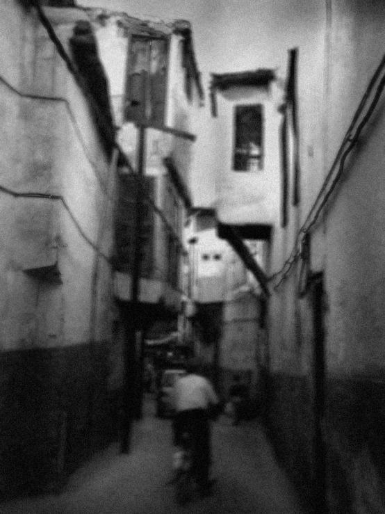 a woman walking down a narrow alley way