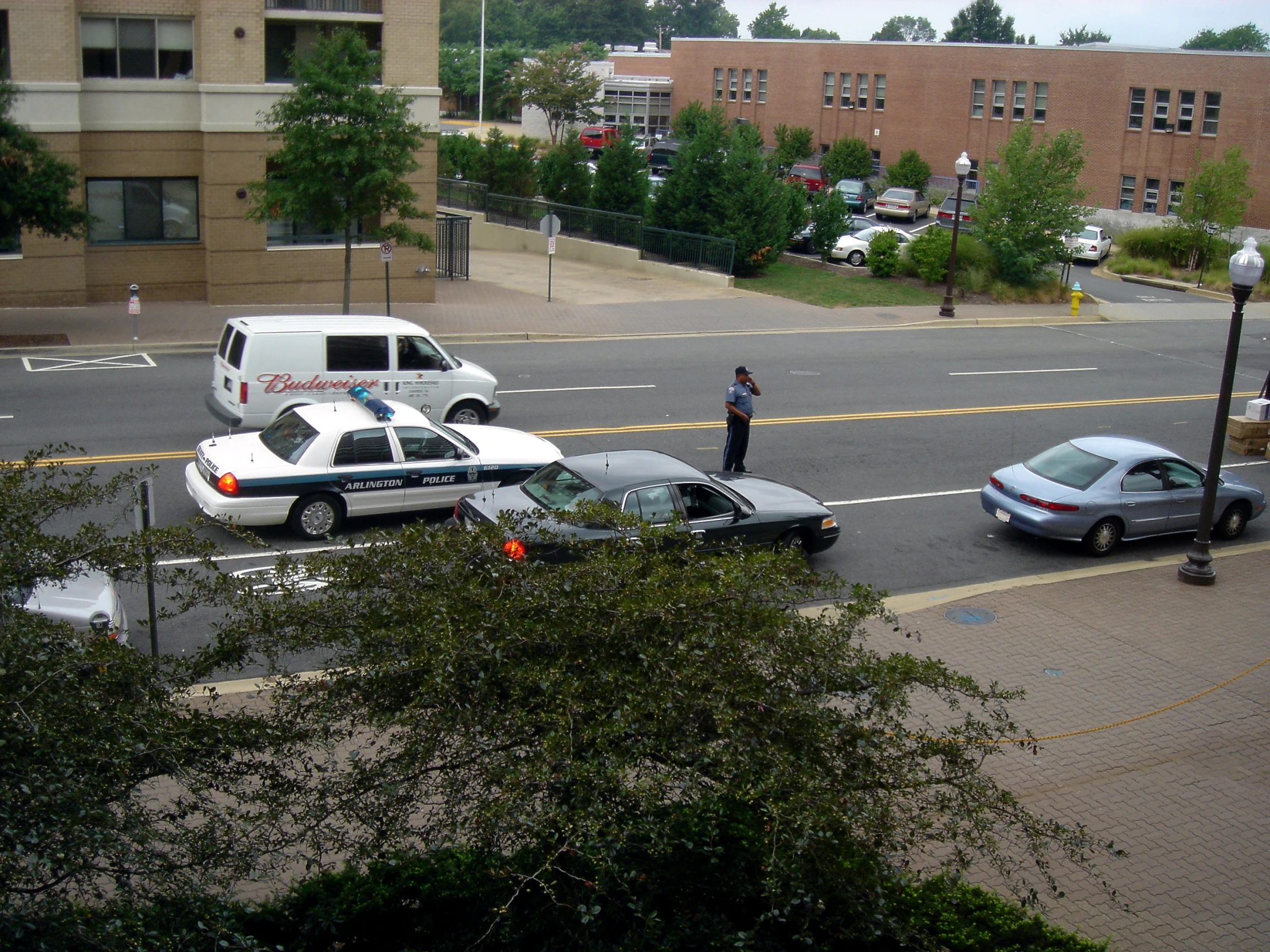 a cop stands at the corner near two police cars