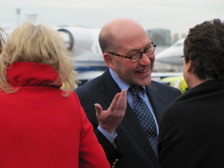 a man wearing glasses talking to two women