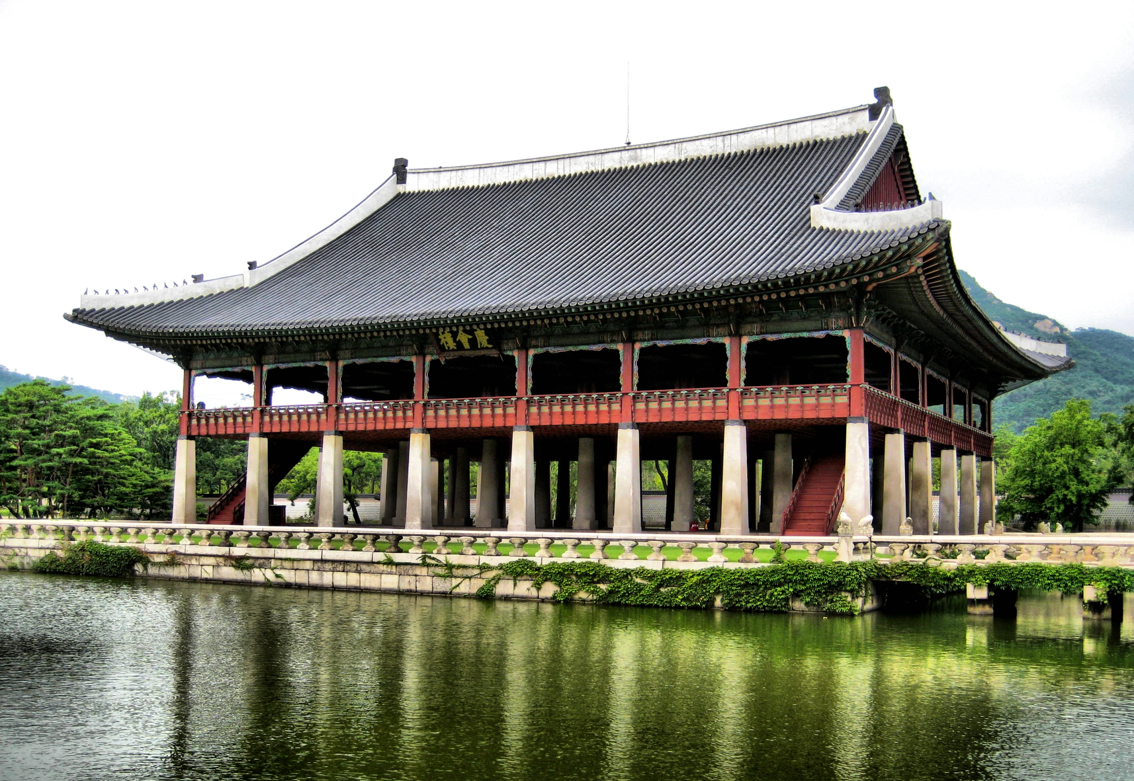 an asian building over looking a lake in front of mountains