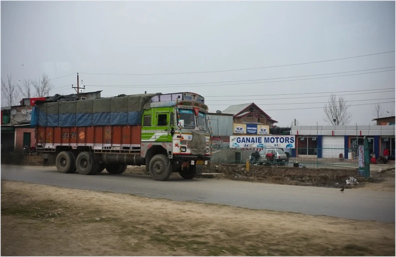 an old truck drives down the road by some houses