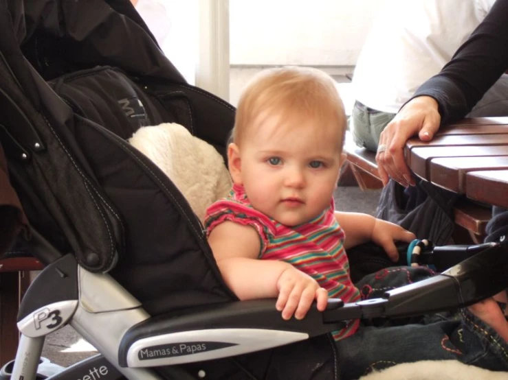 a baby in a stroller that is sitting next to someone