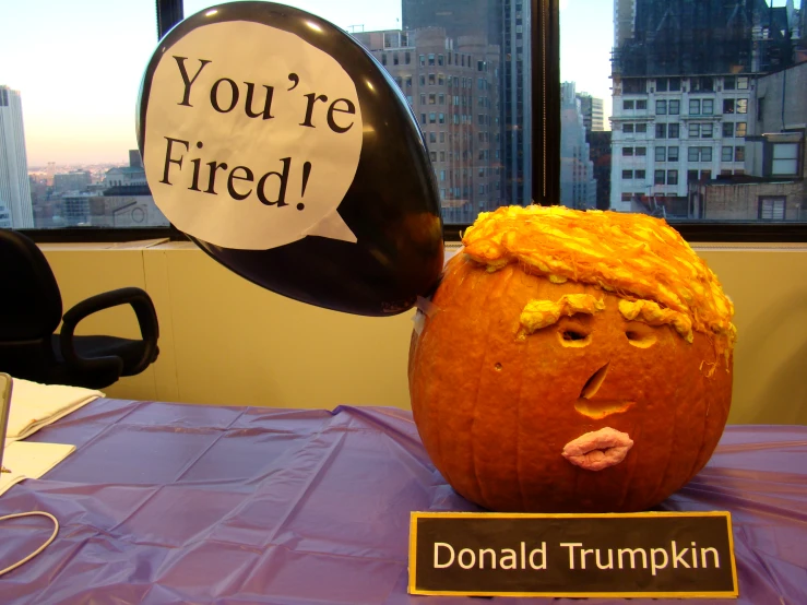 a fake pumpkin shaped like trump is on the table with a sign