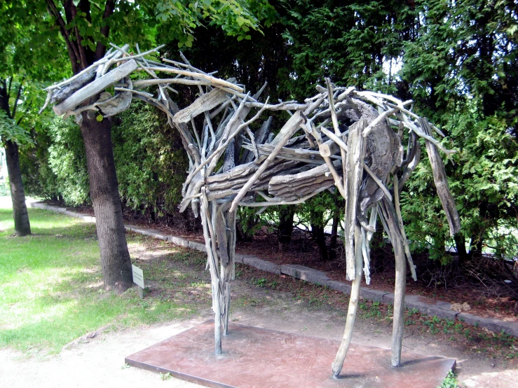 a wooden structure in the park covered in sticks