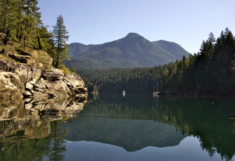 a lake surrounded by forest and surrounded by mountains