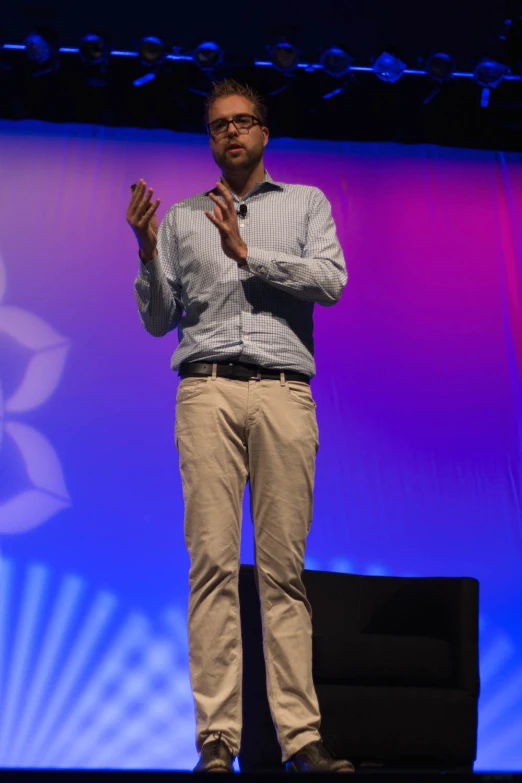 a man standing at a stage in front of a blue and purple background