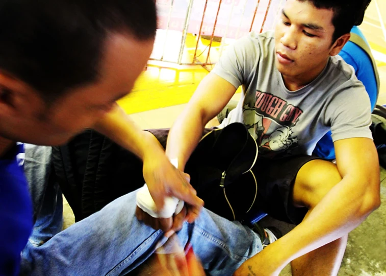 a young man sitting on the floor in a gym