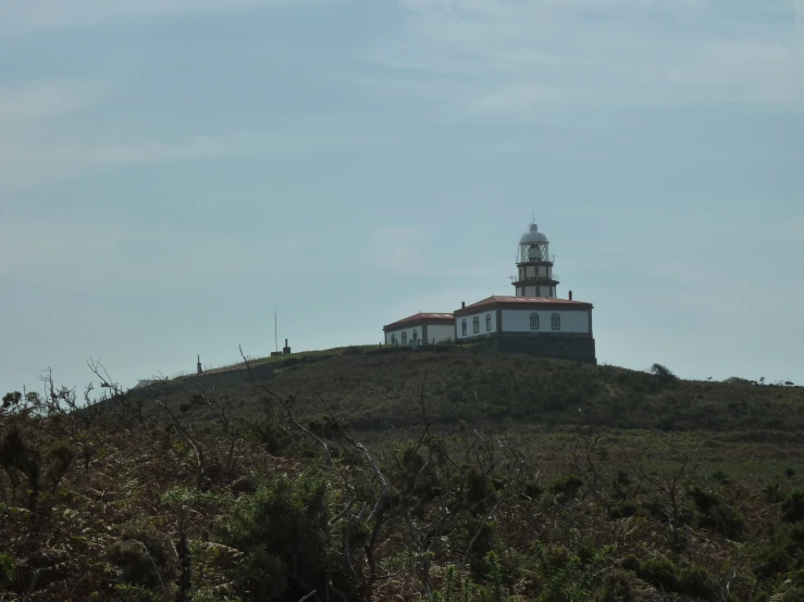 an image of a white lighthouse on a grassy hill