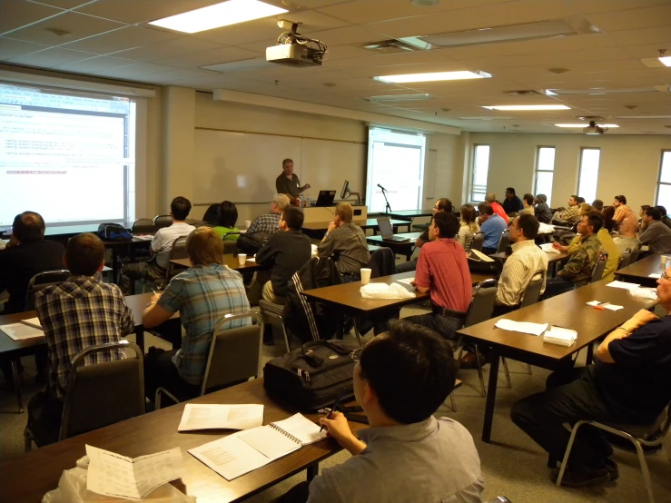 an office with people in rows watching a lecture