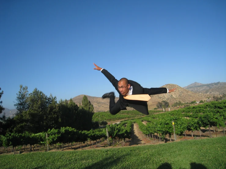 man in suit doing a trick over green grass