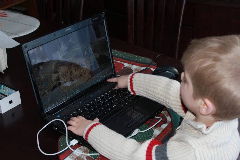 a child is playing on a laptop with headphones