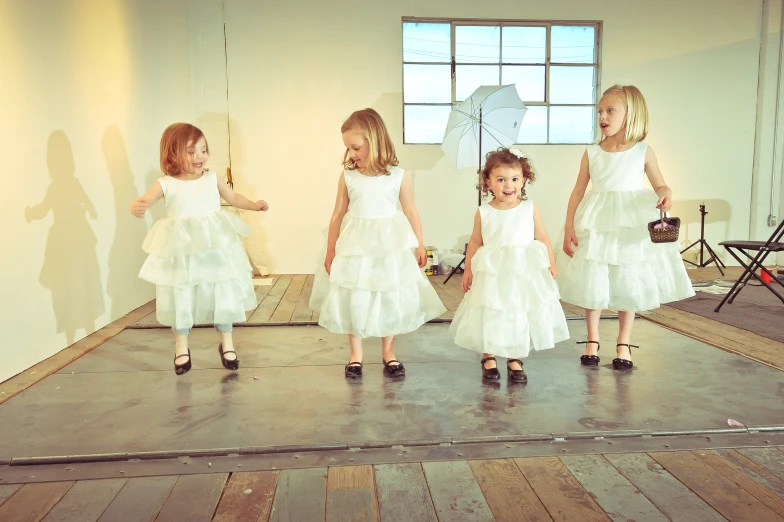 three little girls wearing white dresses and matching shoes