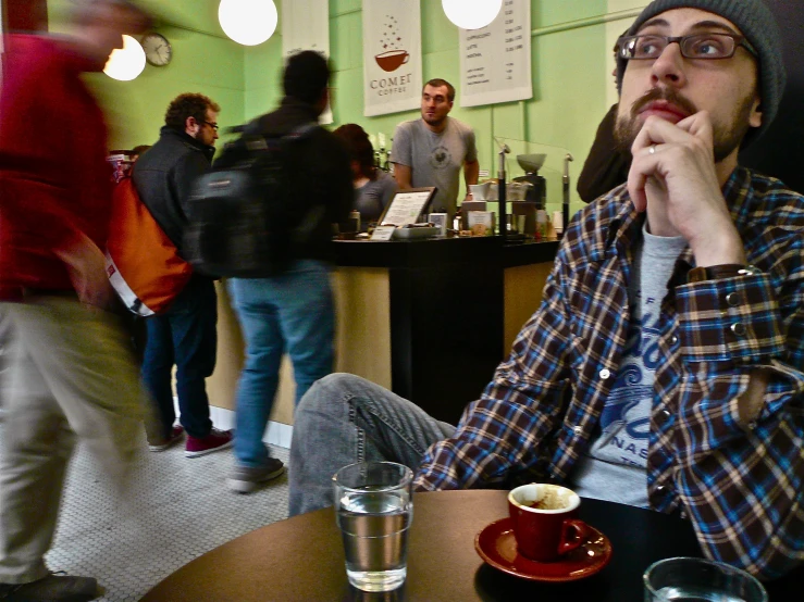 a man sitting in front of a table holding a cup of coffee