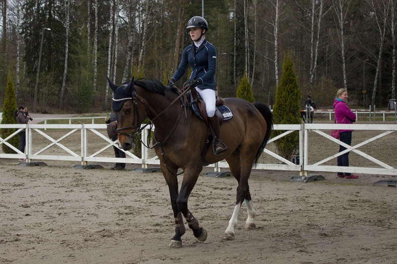 a woman on top of a brown horse walking in dirt