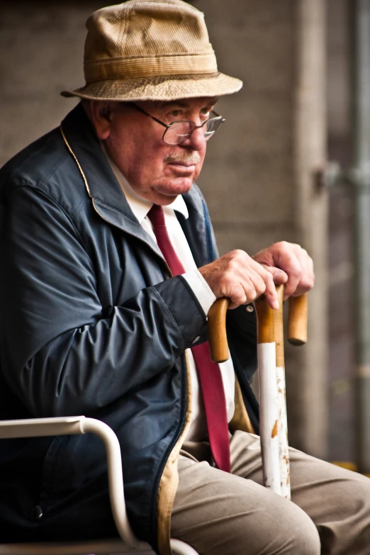 an old man is sitting and holding a cane