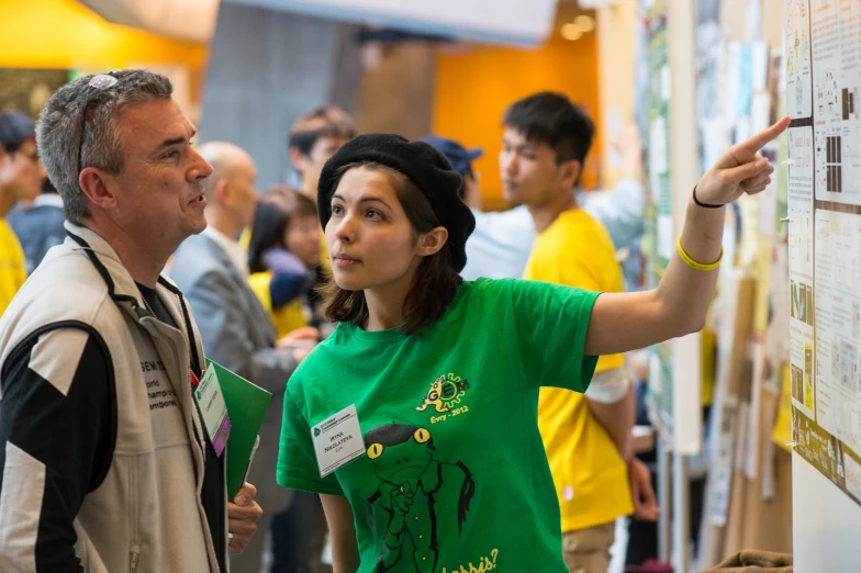 a woman pointing at a bulletin board while another looks on