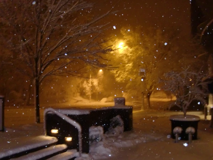 a bench in a snow covered park at night