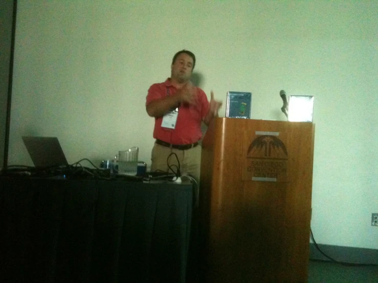 a man is standing at a podium in front of a screen