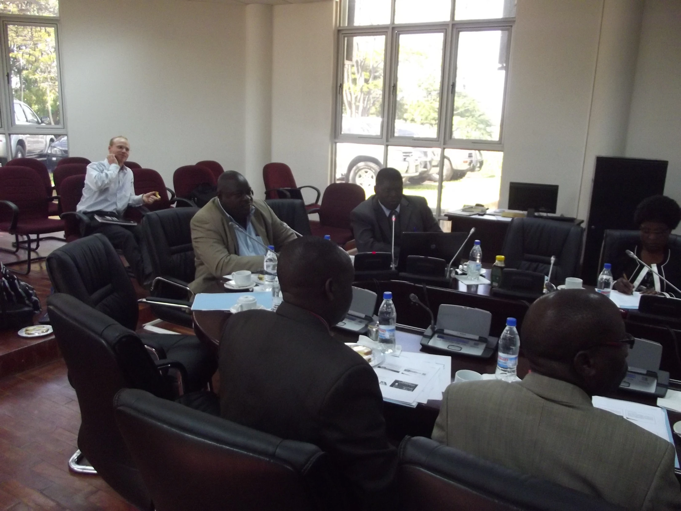 men in suits sitting at a conference room with computers