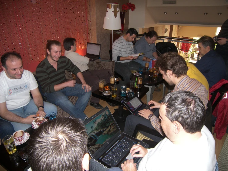 a group of men sitting around each other on their laptops