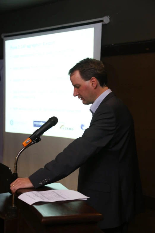 a man at a podium giving a speech at a meeting